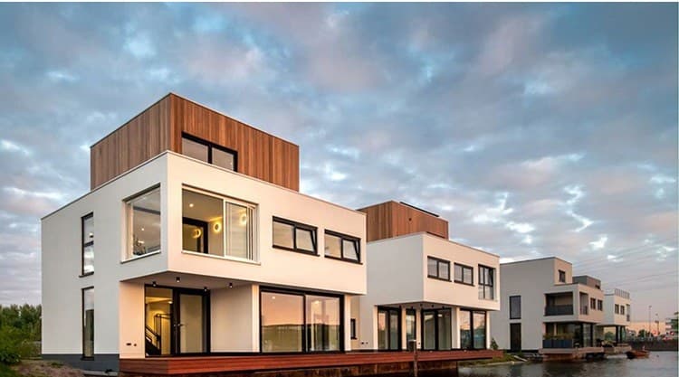 Woonarken met witte en houten volumes aan een kade